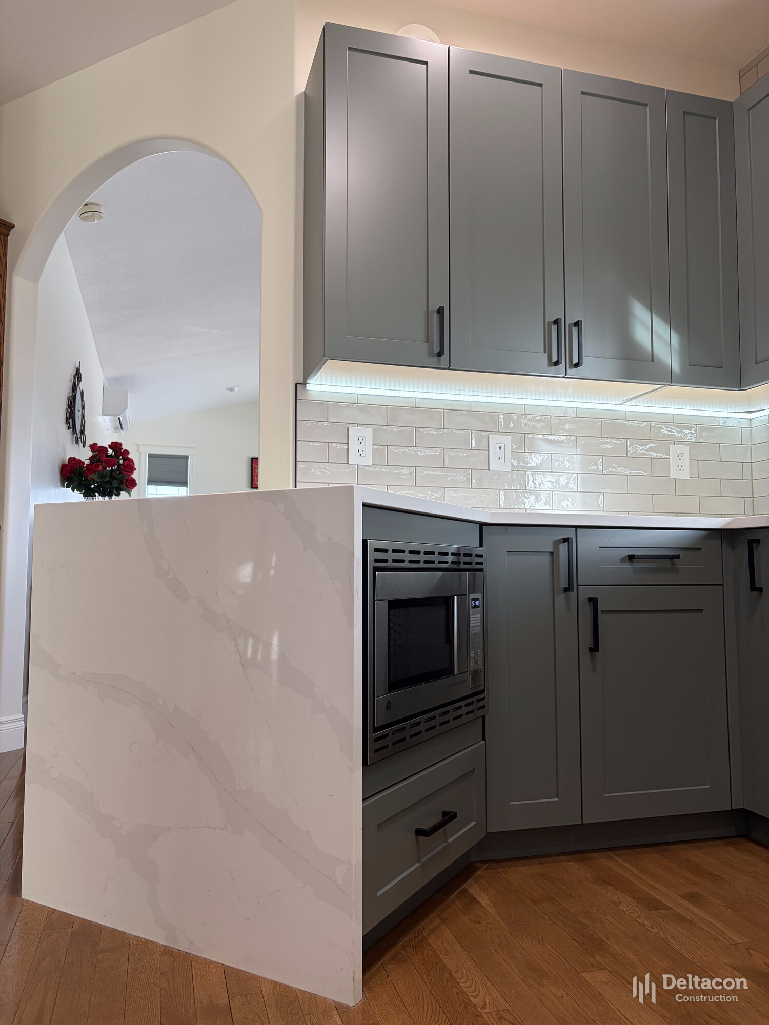 Custom kitchen with quartz waterfall island by Deltacon Construction